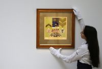 Sotheby's employee adjusts Sgt Pepper collage by Peter Blake and Jann Haworth